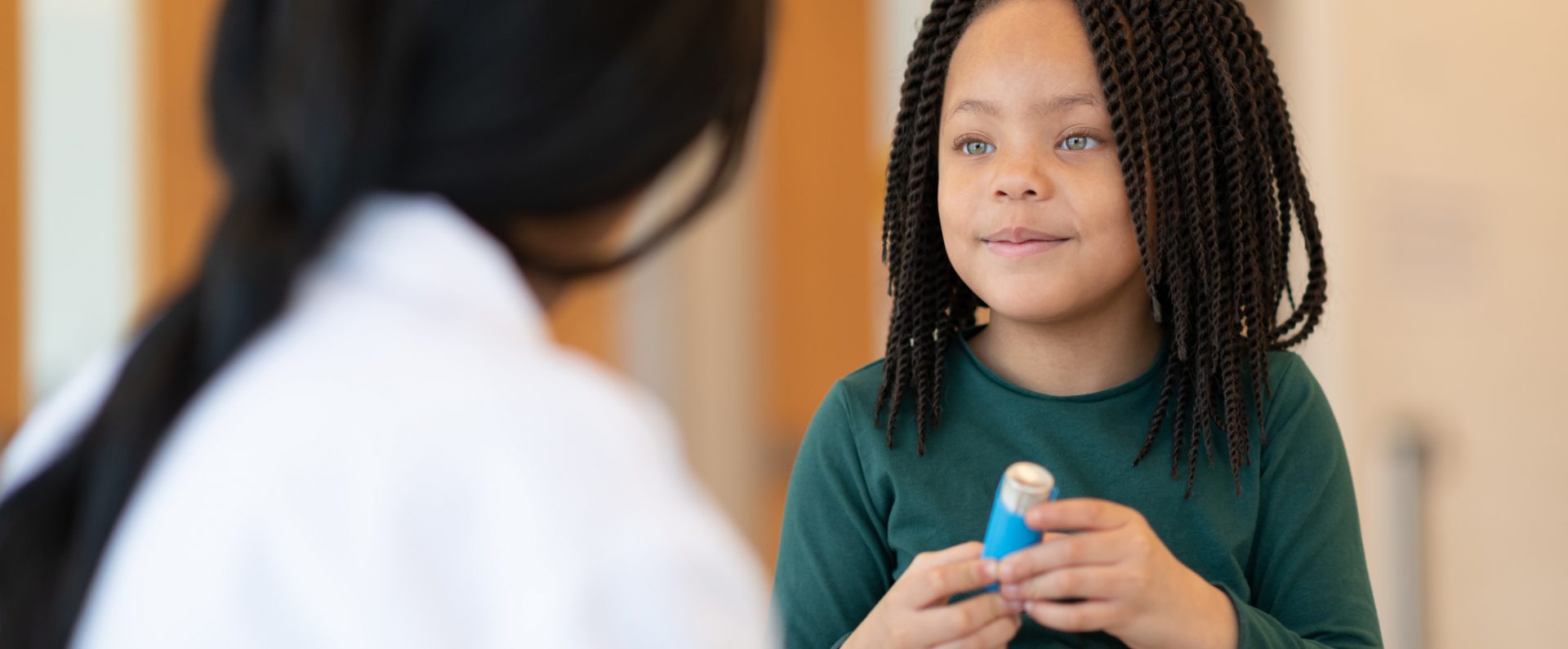 Asthmatic girl learns to use a puffer at a doctor's appointment